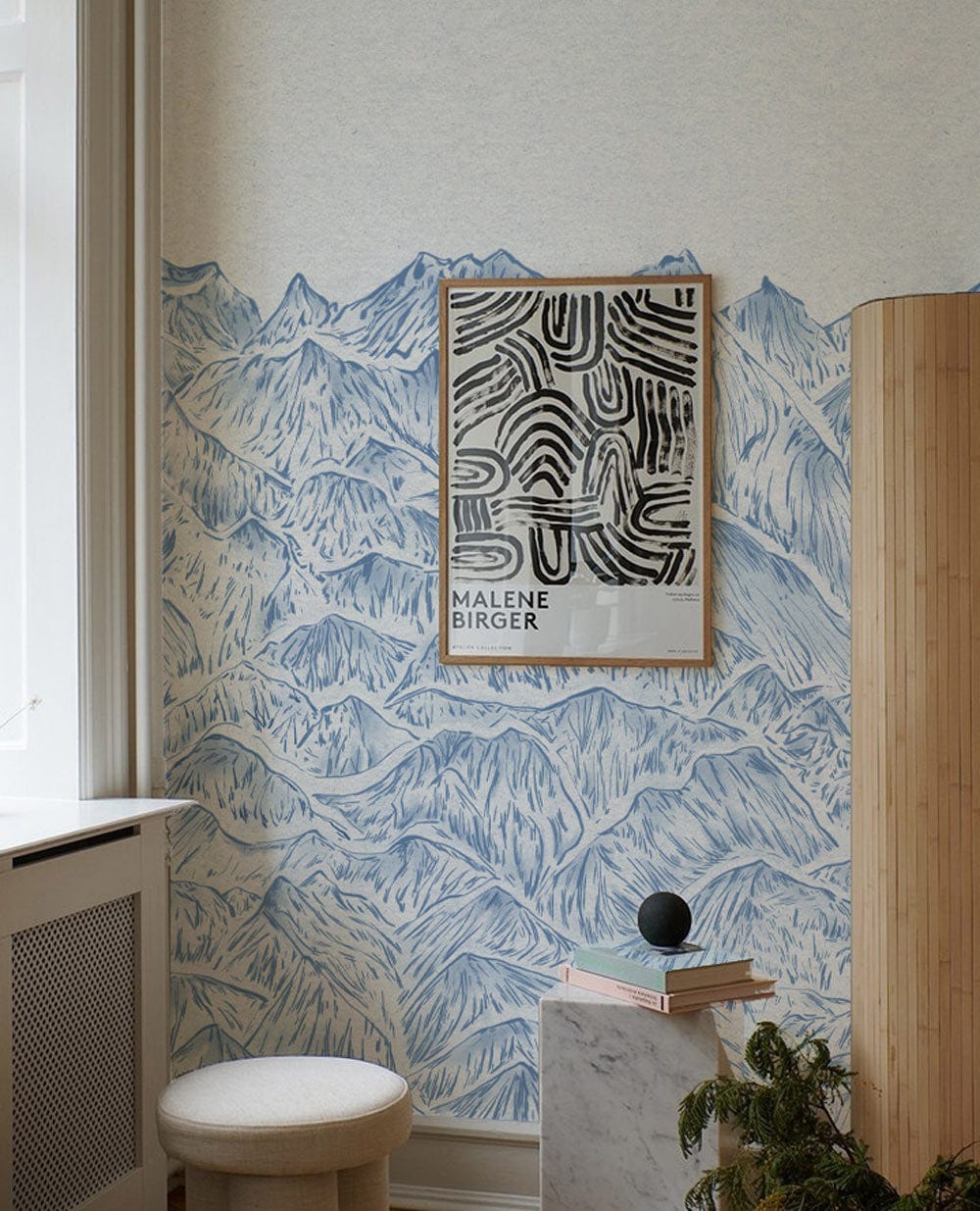 Tranquil Blue Mountain Landscape Mural Wallpaper in stylish room with minimalist stool and modern decor.