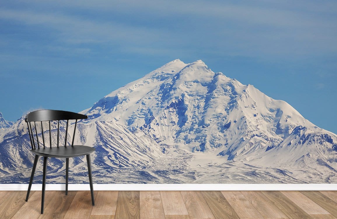 Majestic mural wallpaper, snow-capped mountains, tranquil blue skies, wooden flooring, black chair, scenic design.