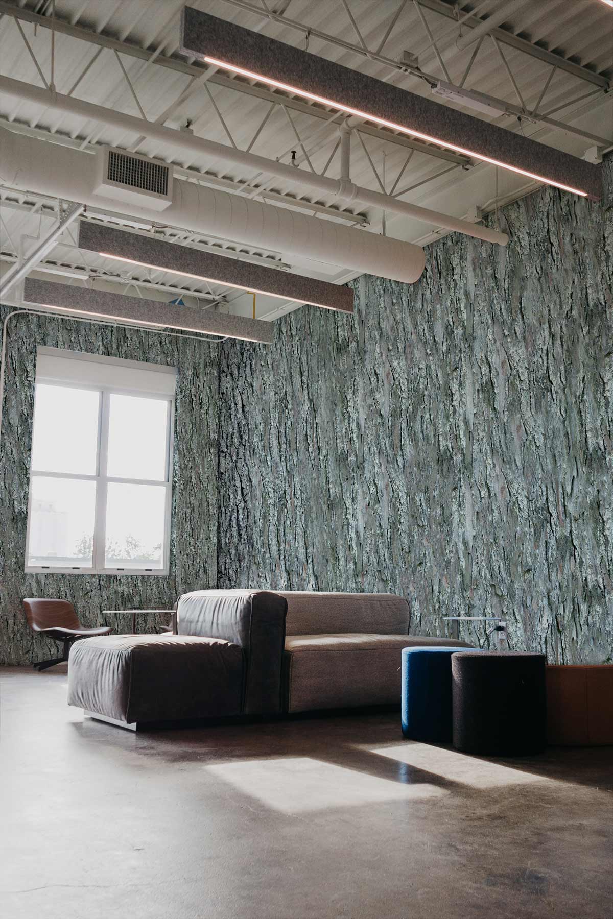 Elegant grey tree bark wallpaper in modern loft with grey sofa, concrete flooring, and ceiling beams.