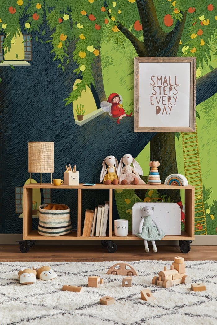 Enchanted Forest Adventure Mural Wallpaper in children's room; playful green design with toys and shelving.