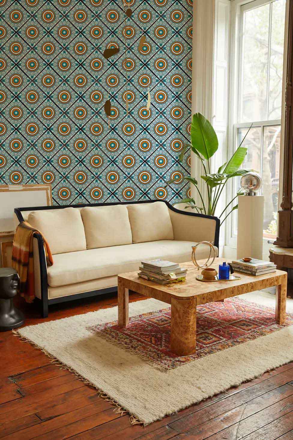Vintage teal and orange geometric wallpaper in stylish living room, cream sofa, wooden flooring.