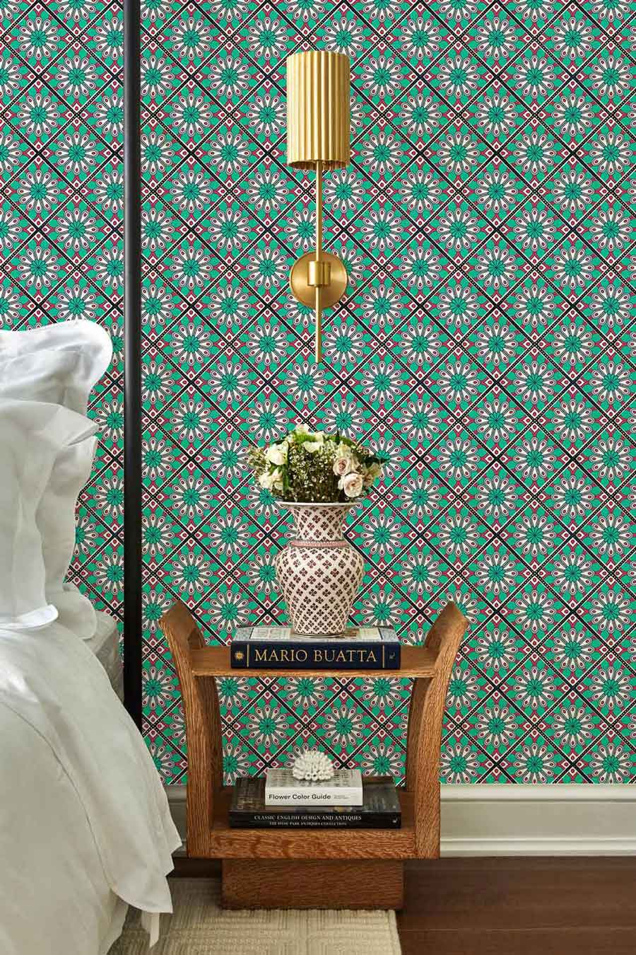 Turquoise and pink floral pattern wallpaper complemented by wooden side table, gold lamp in bedroom.