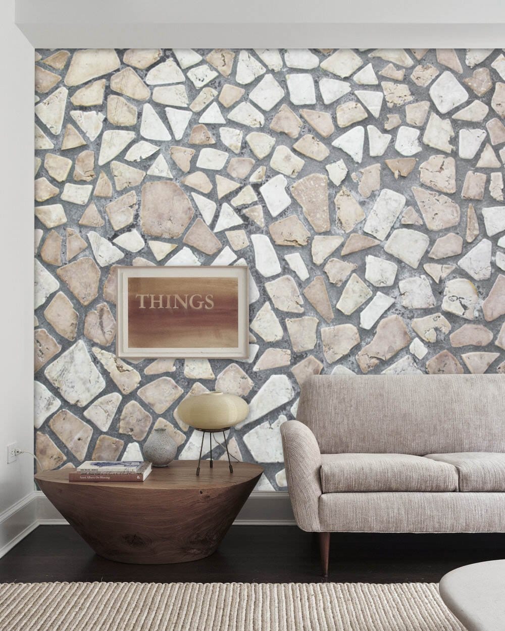 Rustic stone mosaic wall design in living room with neutral sofa, dark flooring, and modern table.