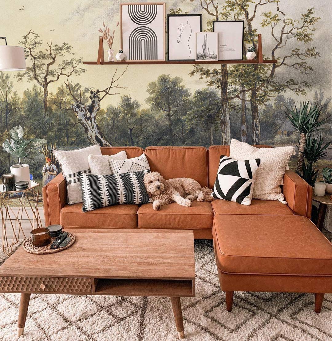Vintage pastoral mural wallpaper with brown sofa, wooden coffee table, and framed art in living room.