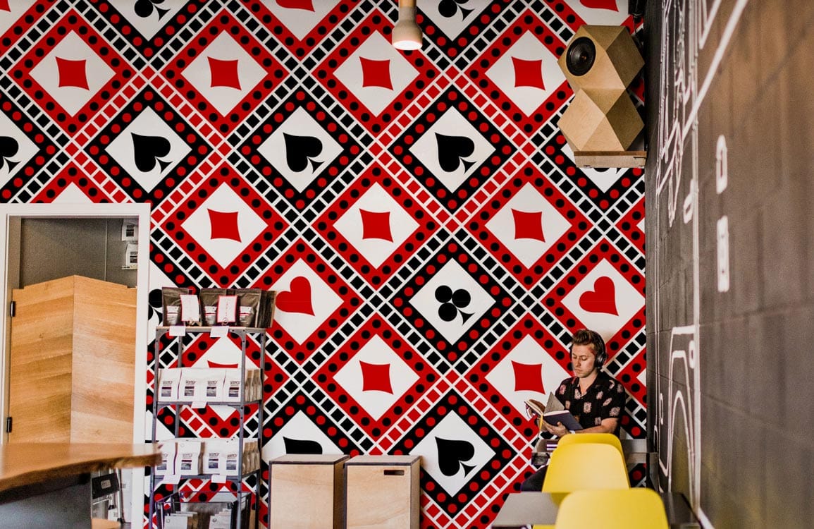 Vintage red and black diamond geometric wallpaper, colourful chairs, modern cafe interior with wooden accents.