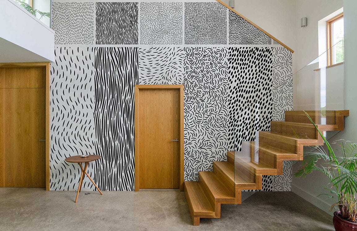 Modern black and white abstract wallpaper in hallway with wooden stairs and doors, concrete flooring.