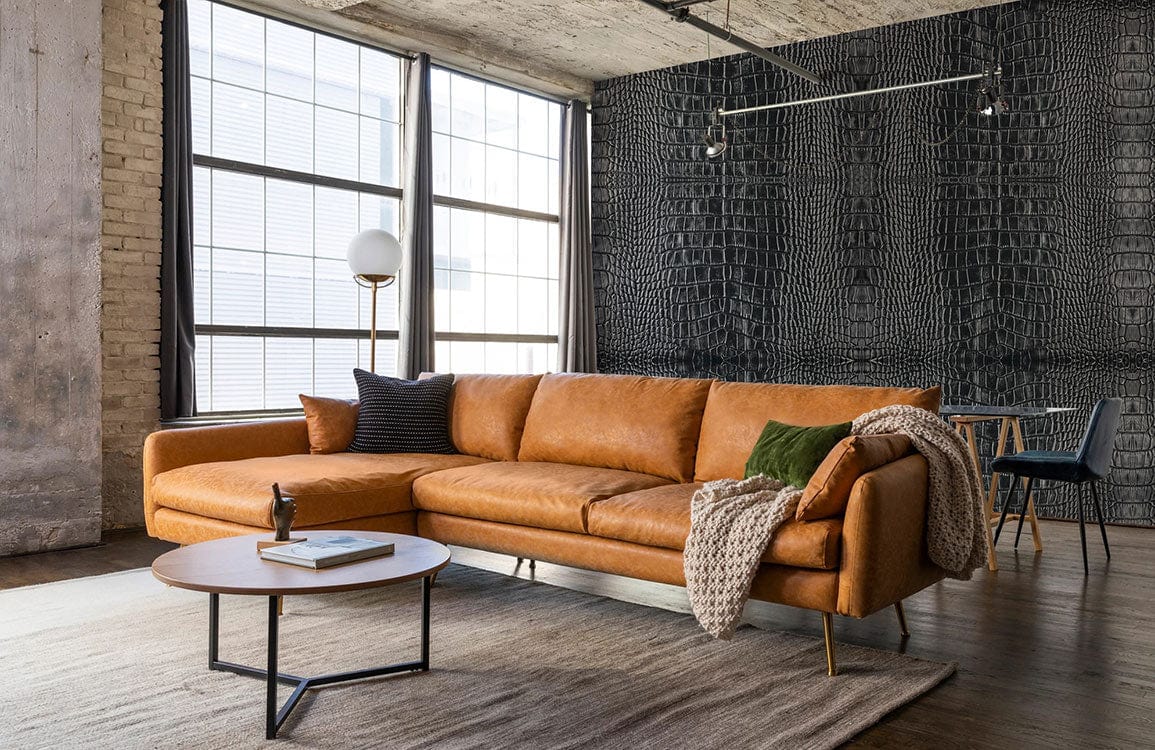 Luxurious faux crocodile textured wallpaper with brown leather sofa, industrial lighting, and wooden flooring.
