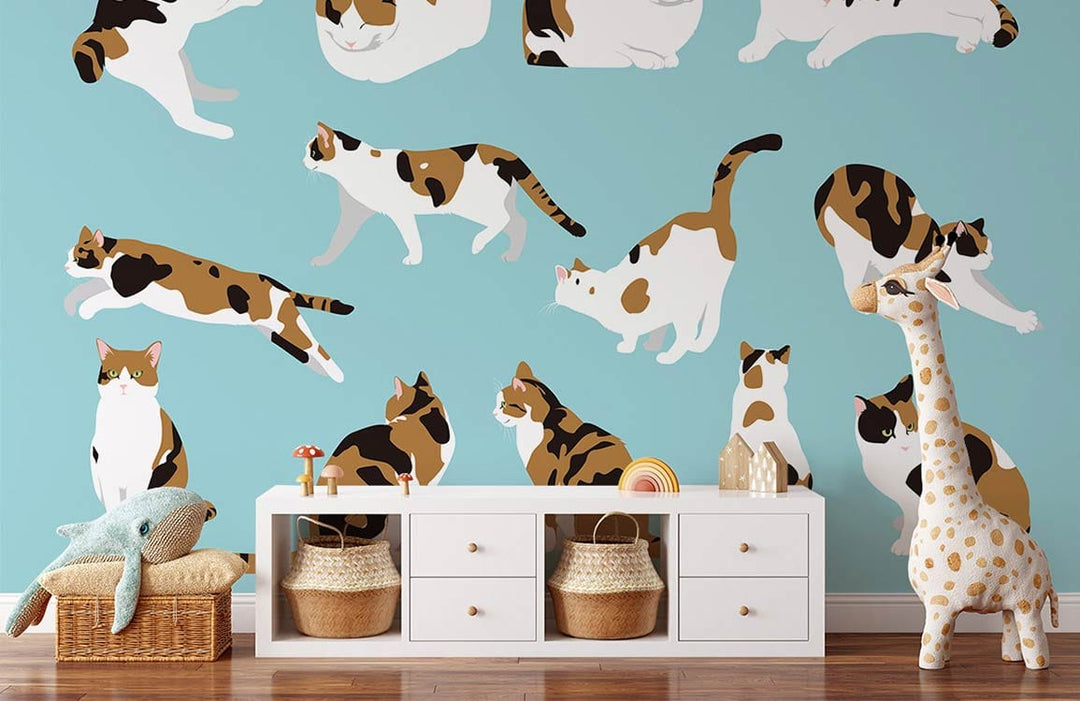 Charming Calico Cats wallpaper in nursery with white dresser, wooden flooring, plush giraffe decoration.