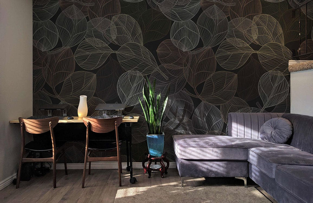 Elegant dark leaf patterned wallpaper in earthy tones features behind grey sofa, desk, light wood flooring.