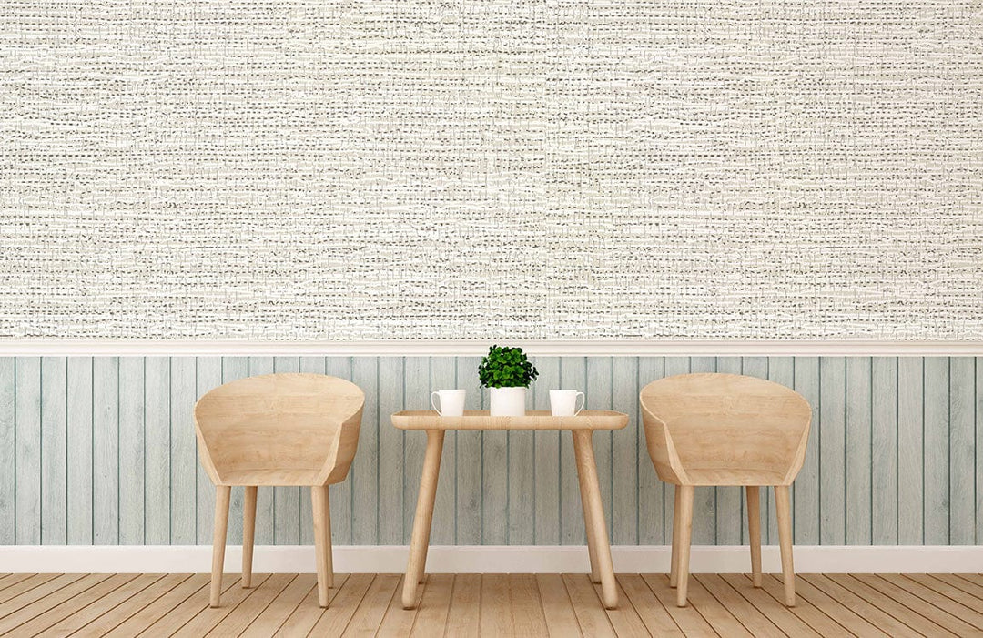 Textured beige linen-effect wallpaper in cosy room with light wood chairs, table, and vertical panelling.
