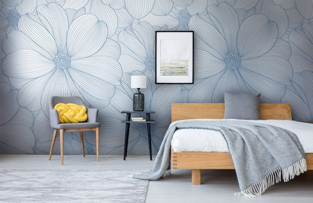 Elegant blue floral wallpaper in modern bedroom, grey chair, wooden bed, framed artwork, wooden flooring.