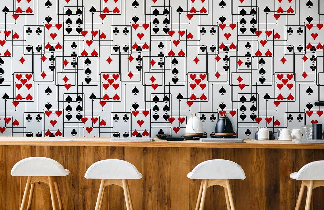 Stylish red black card suit wallpaper in modern kitchen; wooden bar, white stools, appliances.