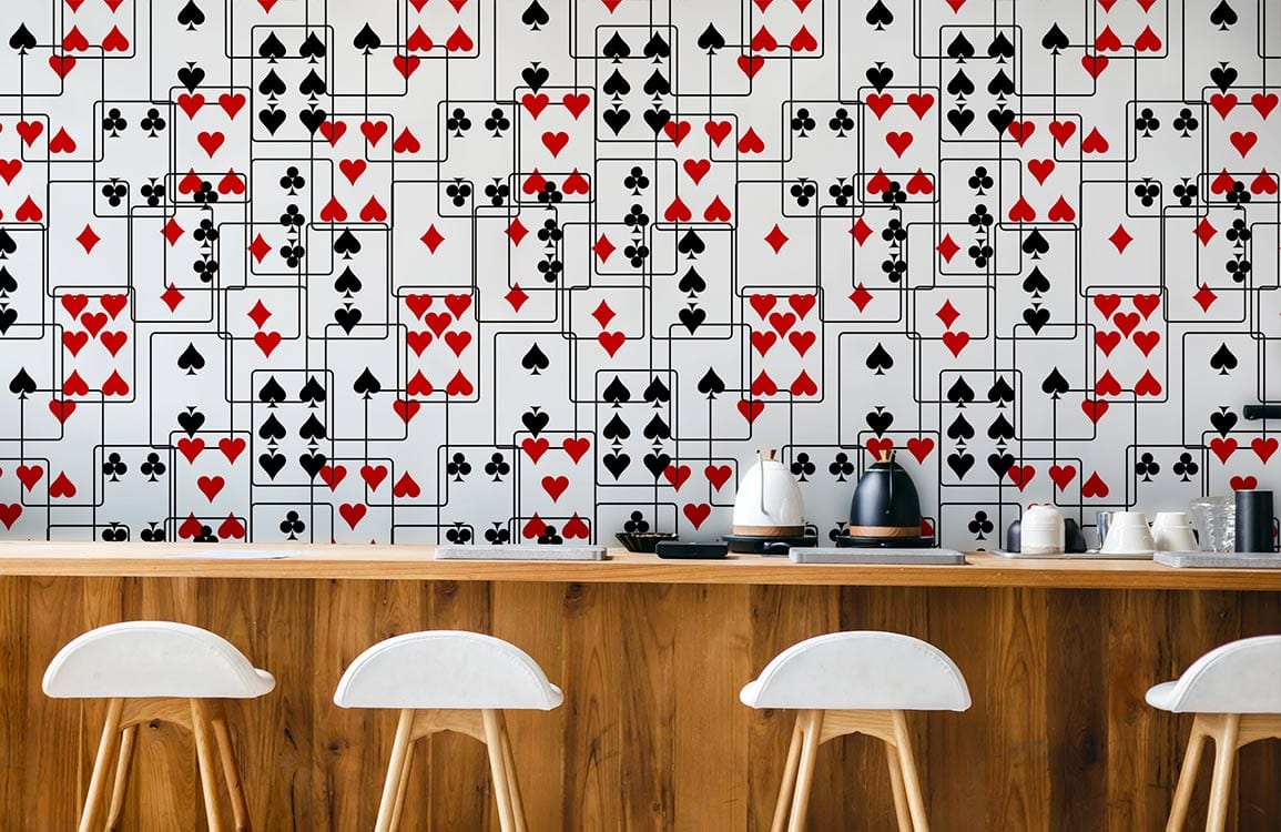 Stylish red black card suit wallpaper in modern kitchen; wooden bar, white stools, appliances.