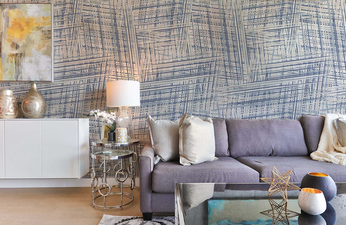 Vintage blue geometric criss-cross wallpaper, grey sofa, glass coffee table, and modern living room decor.