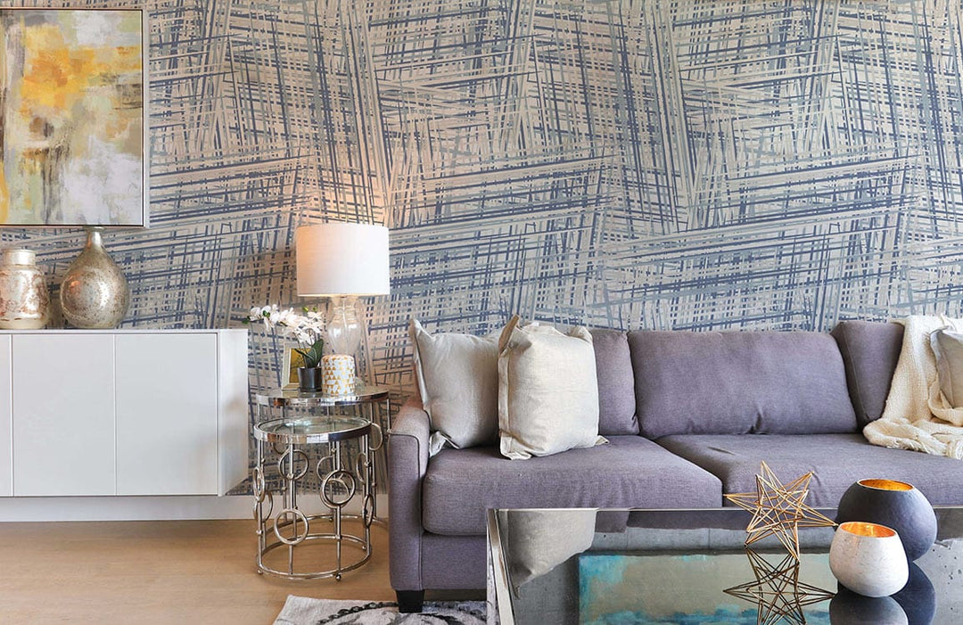 Vintage blue geometric criss-cross wallpaper, grey sofa, glass coffee table, and modern living room decor.