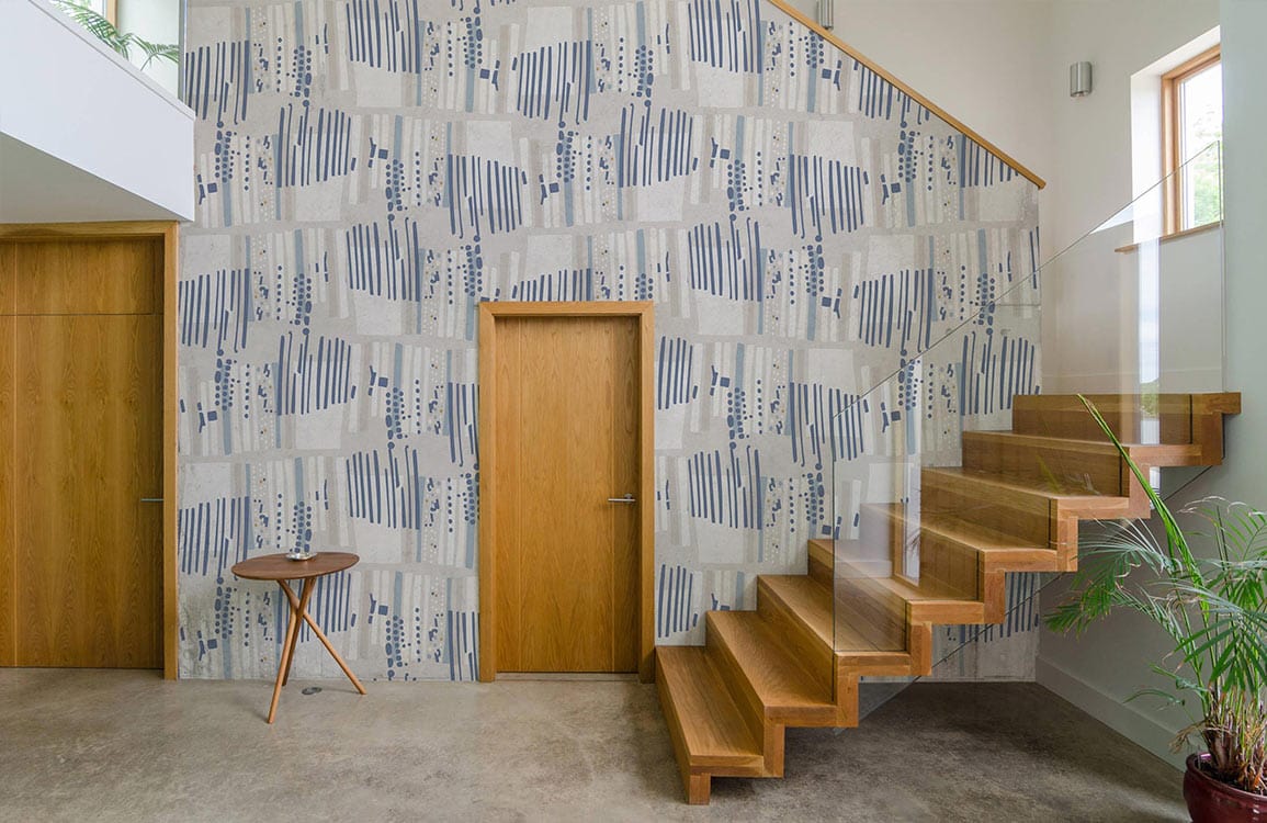Contemporary beige and blue geometric patterned wallpaper with wooden staircase and concrete flooring in modern space.