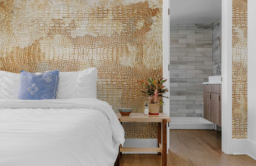 Textured beige crocodile skin wallpaper in bedroom with white bedding, wooden floor, and blue cushion.