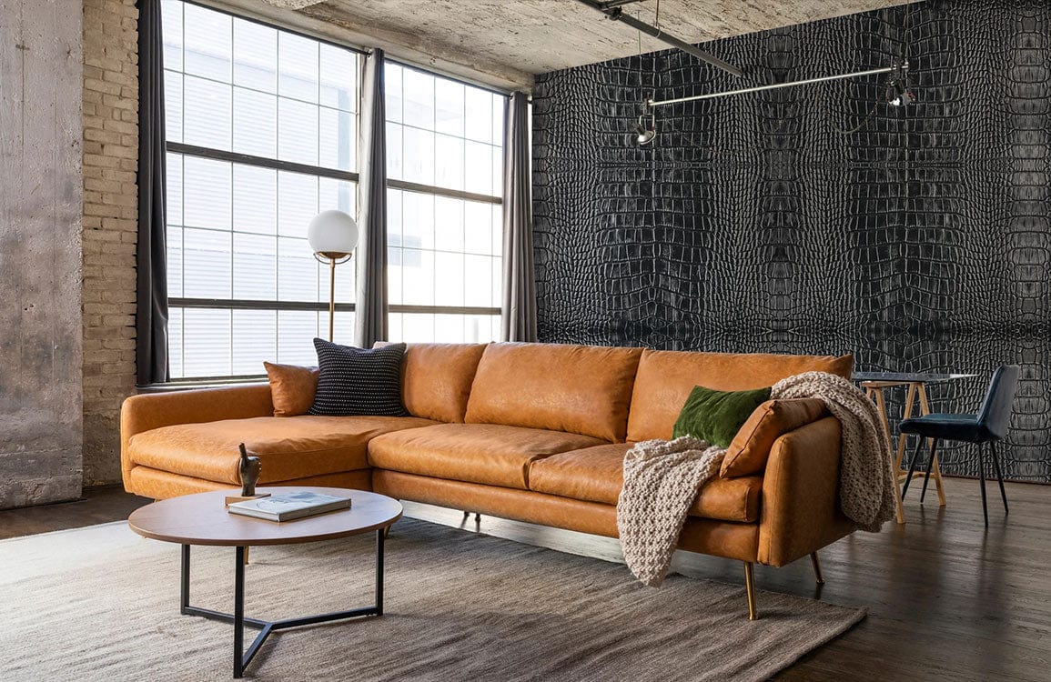 Tan leather sofa in modern room with grey crocodile skin pattern wallpaper, wooden flooring, chic decor.