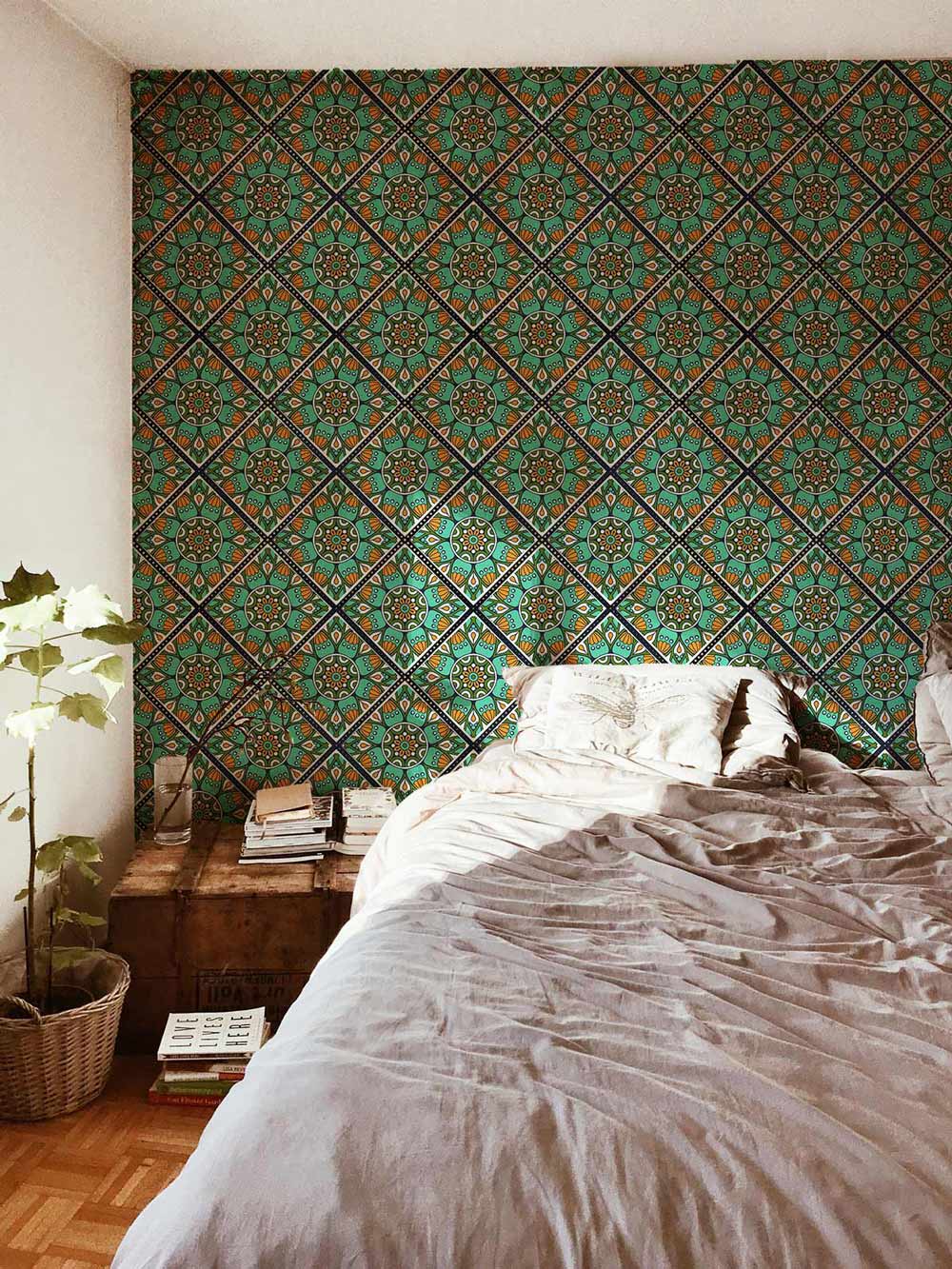 Bedroom with vintage turquoise-orange geometric wallpaper, grey bedspread, wooden flooring, and bedside table.