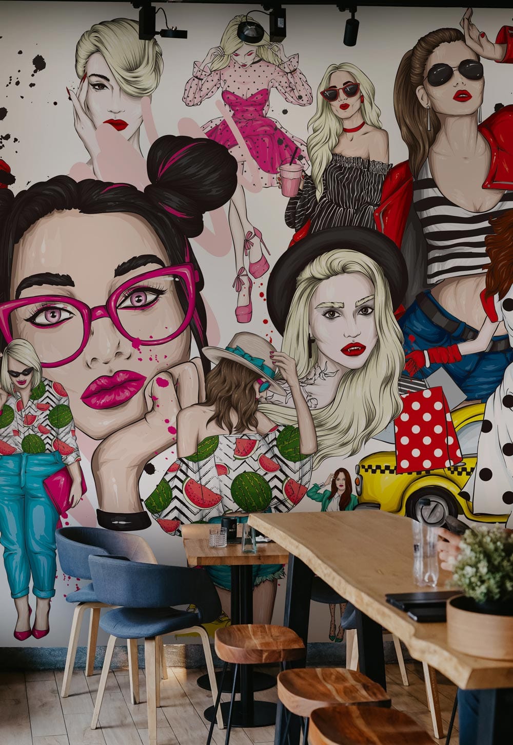 Contemporary mural wallpaper with fashion icons, vibrant reds; features modern dining furniture and wooden flooring.