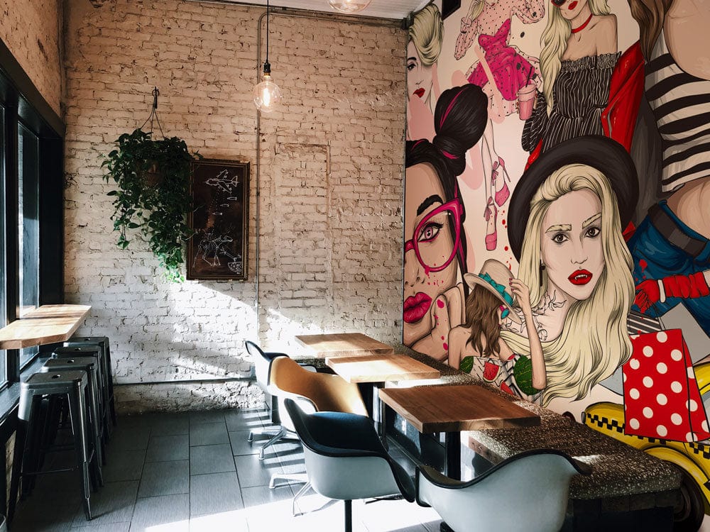 Vibrant fashion mural wallpaper, chic red, artistic café setting, brick wall, modern furniture, hanging light.