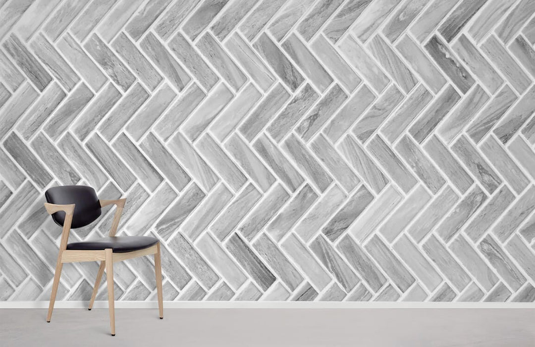 Grey Chevron patterned wallpaper with modern texture, featuring black chair and light floor in a minimalist room.