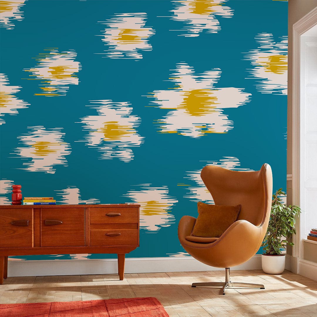 Bold teal wallpaper with daisies, featuring vintage style. Orange chair, wooden sideboard, tiled floor.