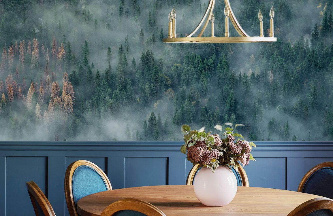 Foggy Forest Mural Wallpaper enhances dining area with wooden table, chairs, blue panelling, chandelier.