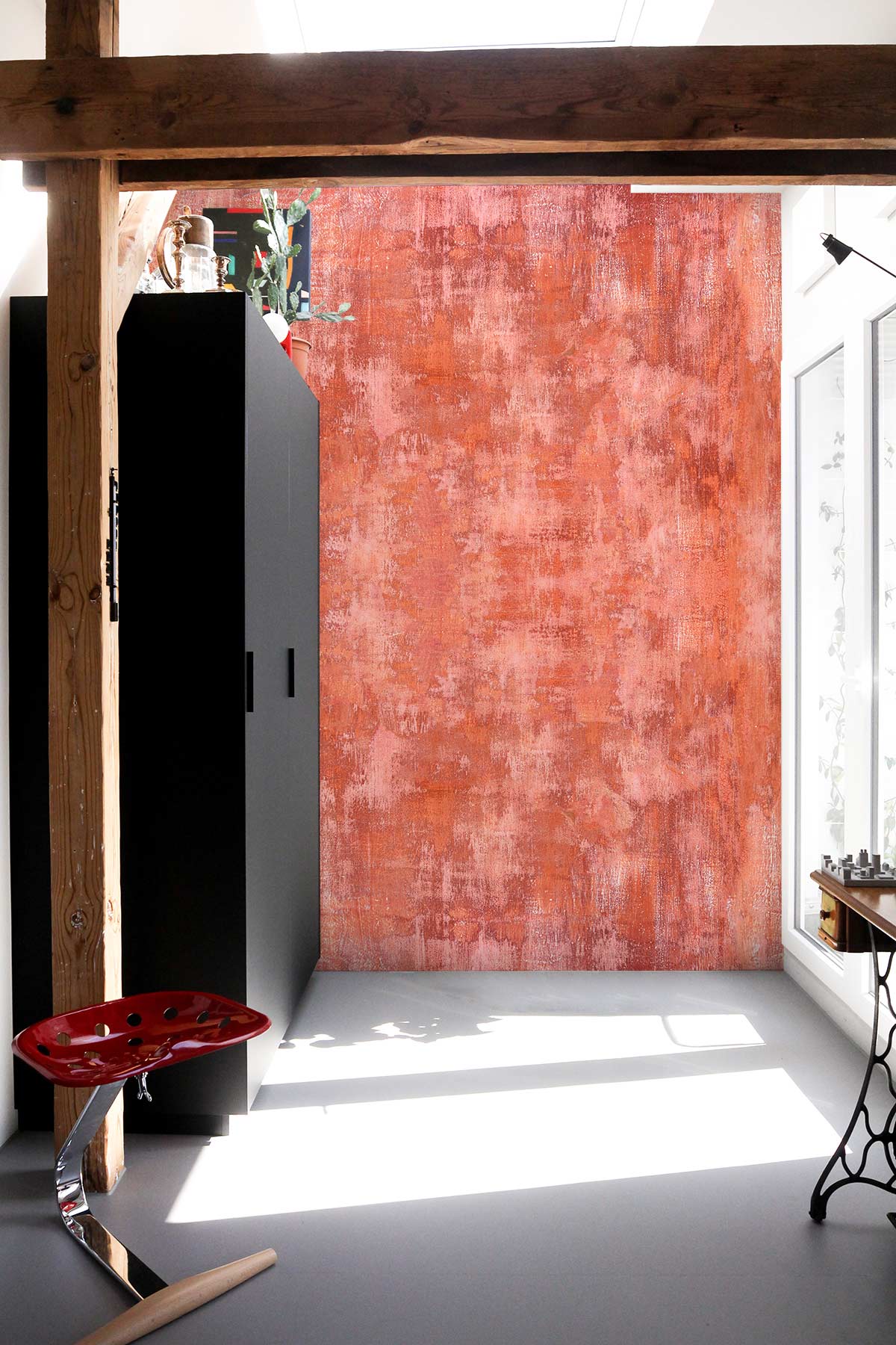 Rustic terracotta abstract wallpaper, warm earthy tones, modern black wardrobe, minimalist red stool, wooden beam.