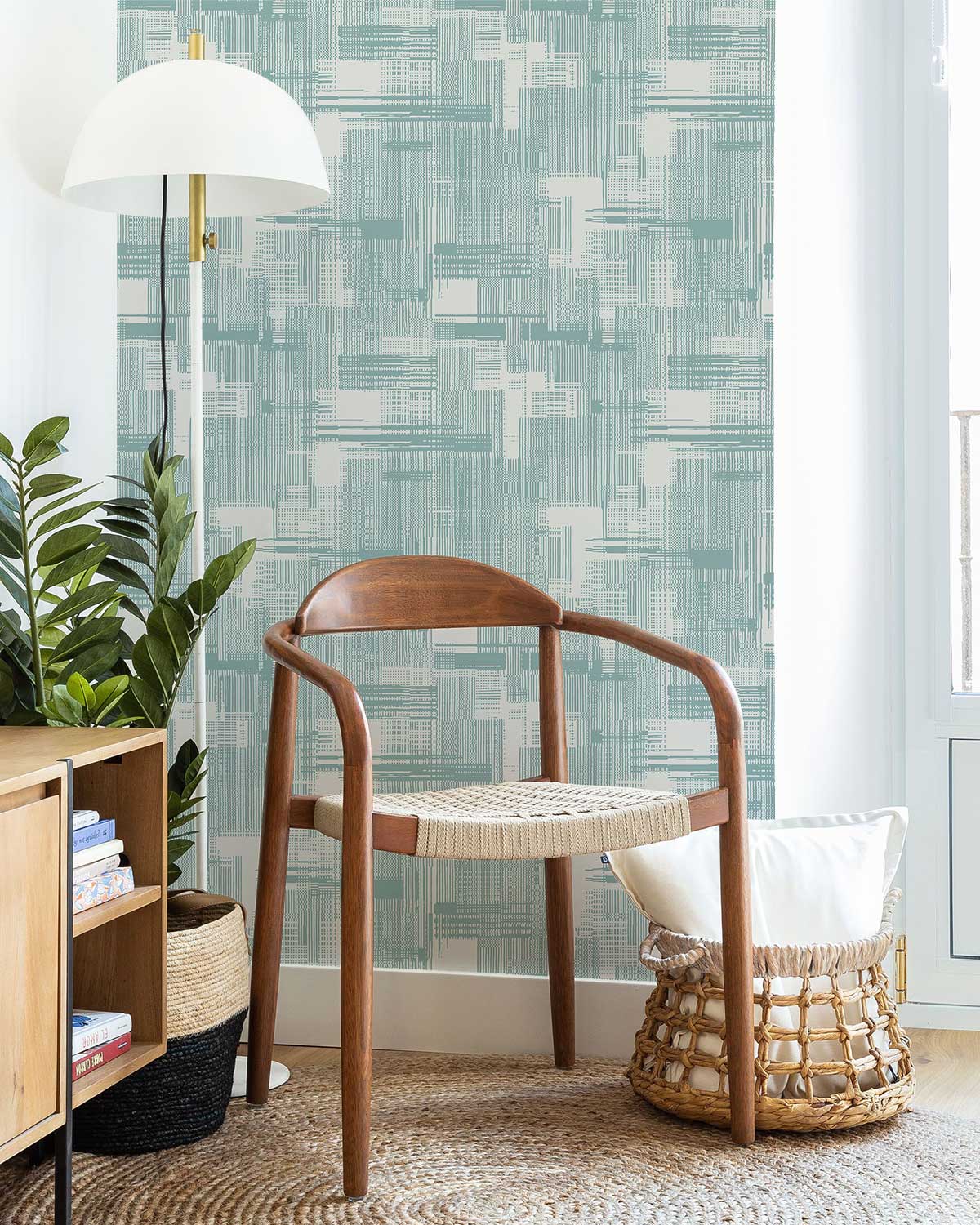Mint geometric pattern wallpaper in modern room with wooden chair, wicker basket, and floor lamp.