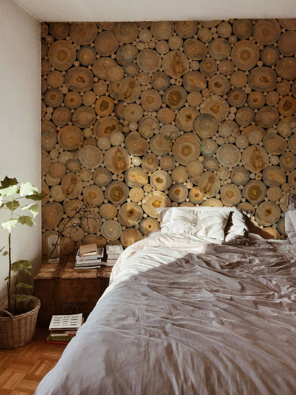 Rustic Earth Tones log slice wallpaper, bedroom interior, wooden flooring, grey bedding, natural decor.