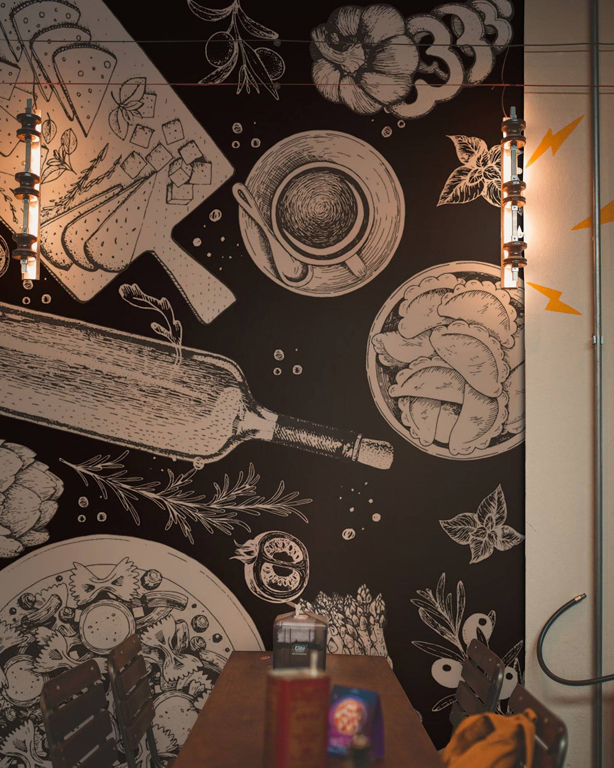 Monochrome Vintage Kitchen Sketches Mural Wallpaper, rustic charm, industrial lights, wooden chairs, dining area.