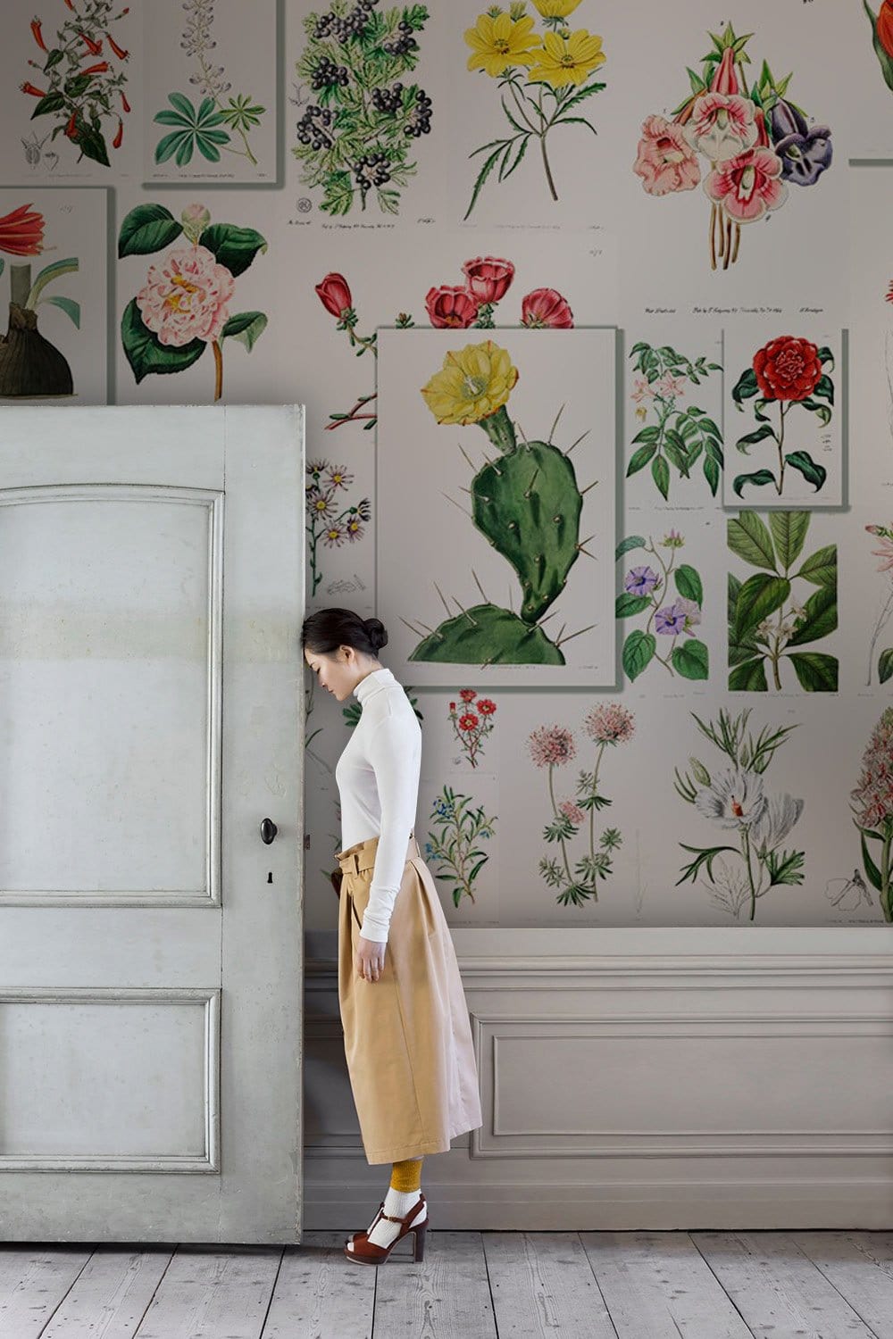 Vintage botanical floral mural wallpaper in room with white door and light wooden flooring.