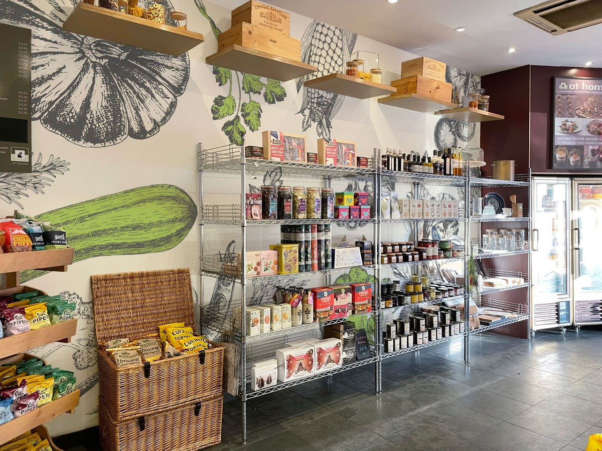Botanical vegetable sketch wallpaper in rustic store with metal shelves, slate flooring, and wicker basket display.