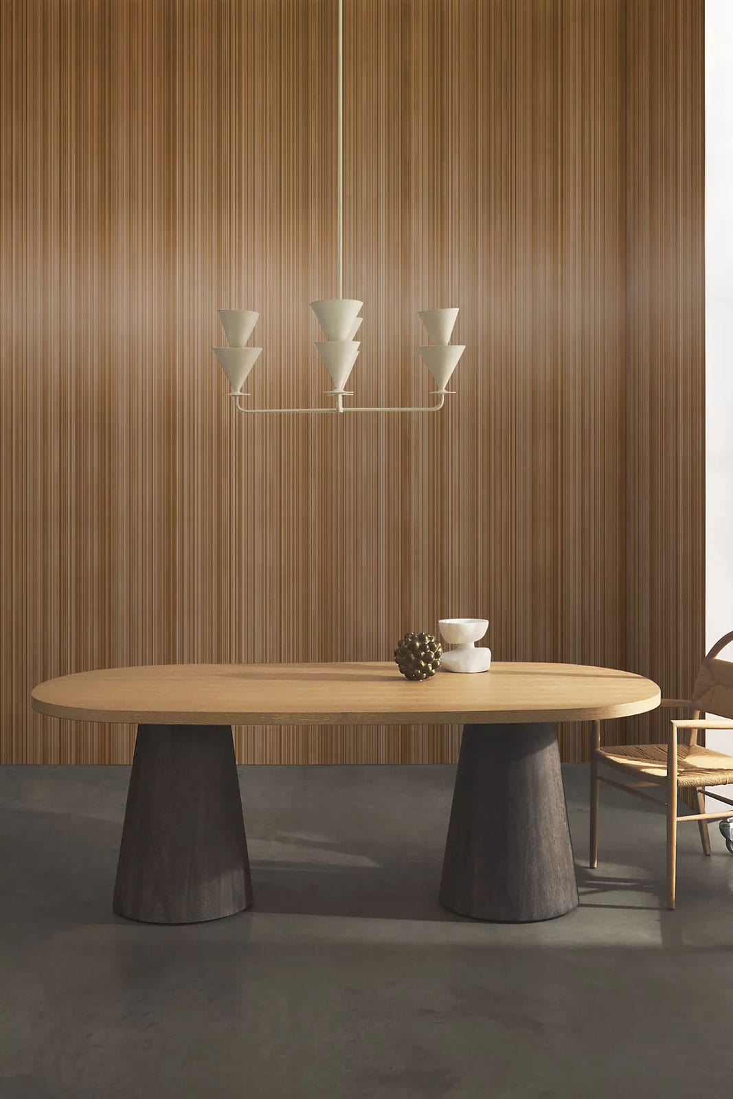 Modern dining room with wooden table, matching chairs, wood-panelled wall, and geometric pendant light.