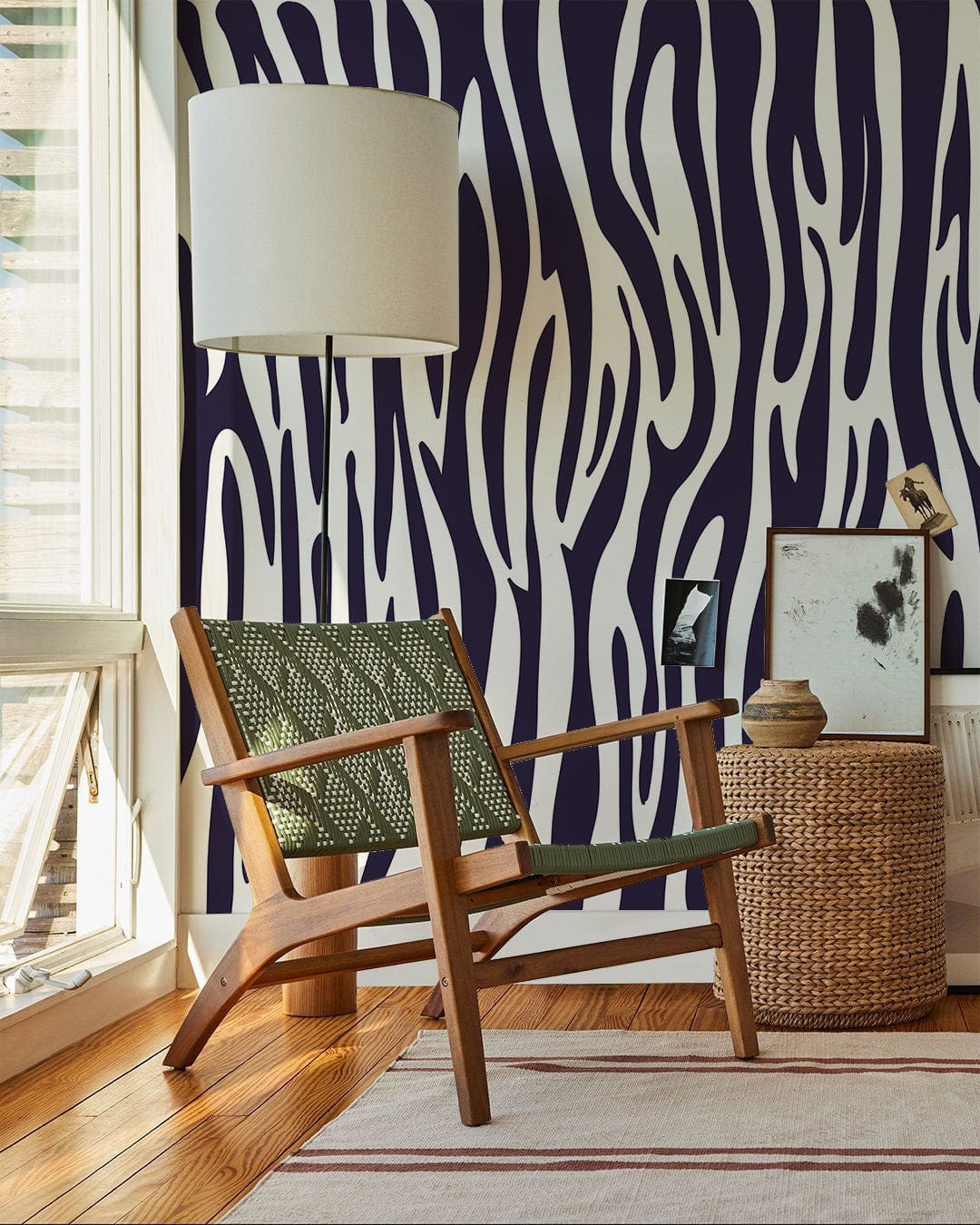 Monochrome zebra print wallpaper with wooden armchair, woven basket, white lamp, and hardwood flooring.