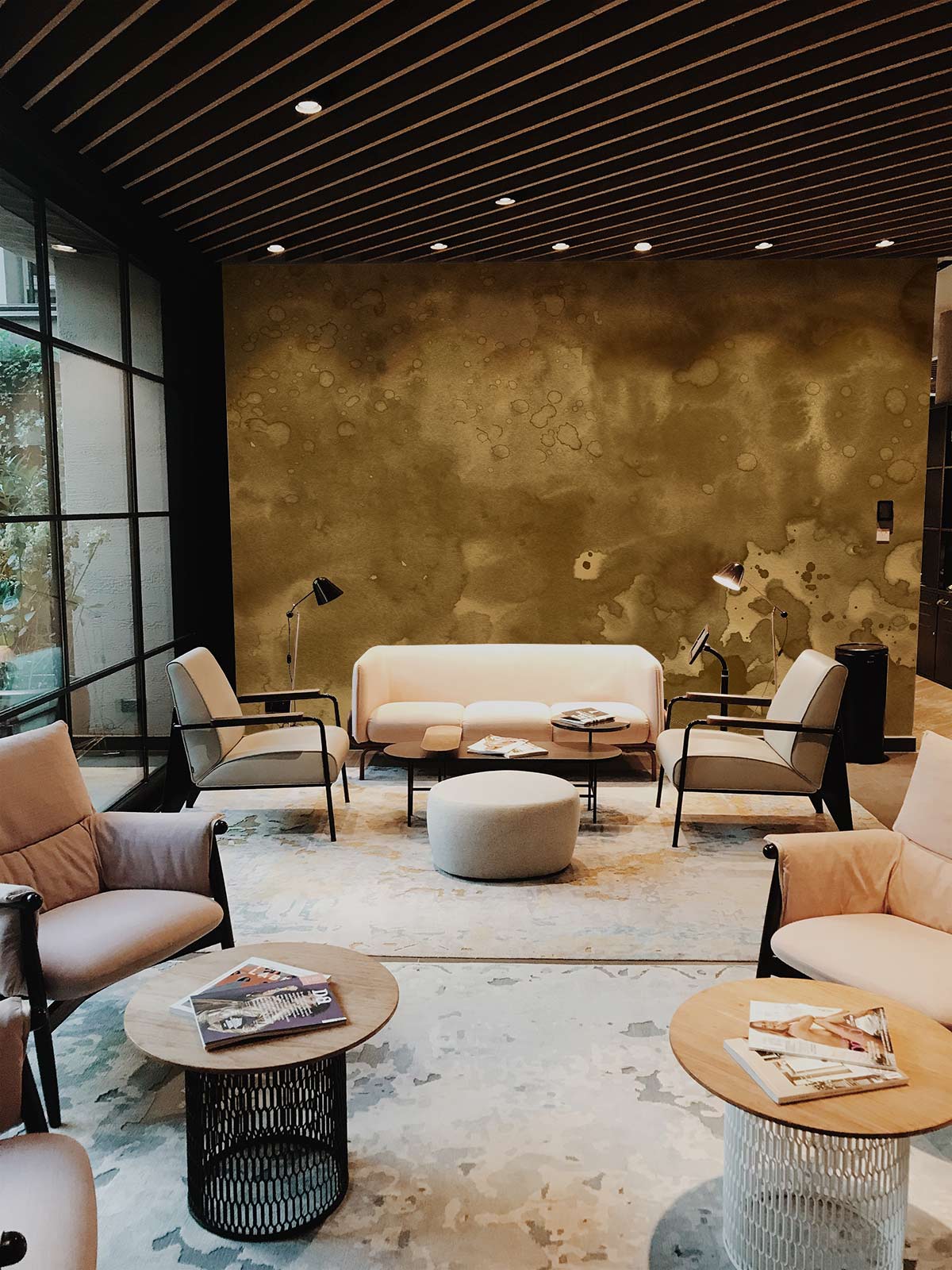 Modern lounge featuring Vintage Earthy Tones Abstract Mural Wallpaper, cream sofa, armchairs, and wooden flooring.