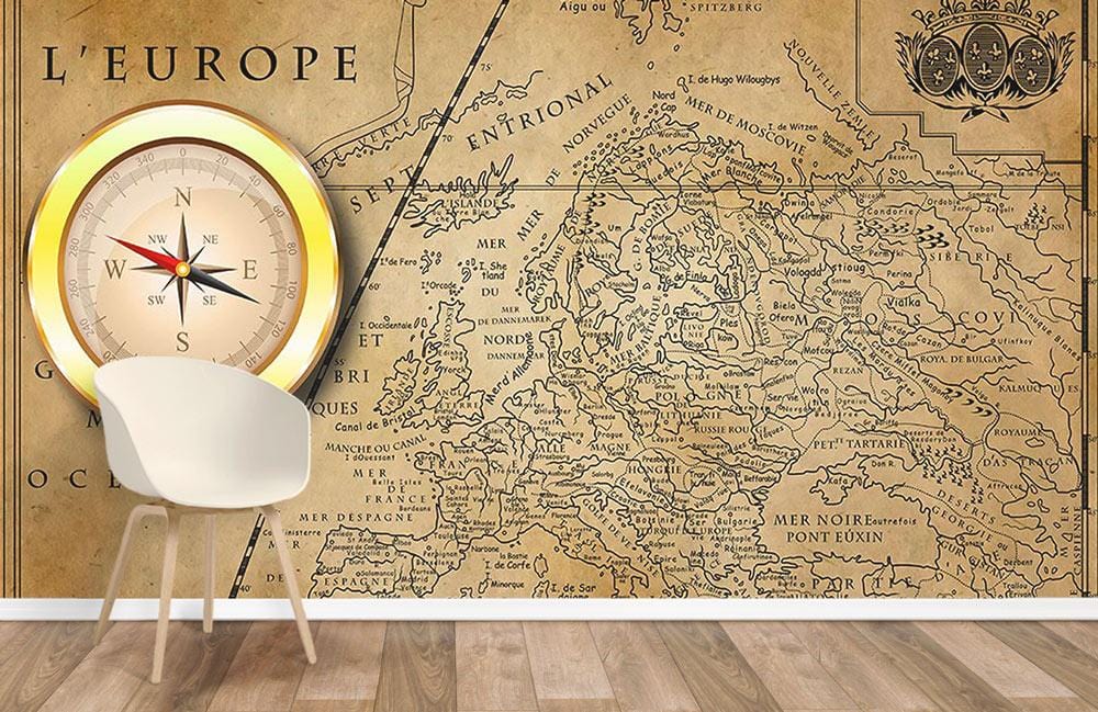 Vintage European map mural wallpaper in antique brown with nautical compass, white chair, wooden flooring.