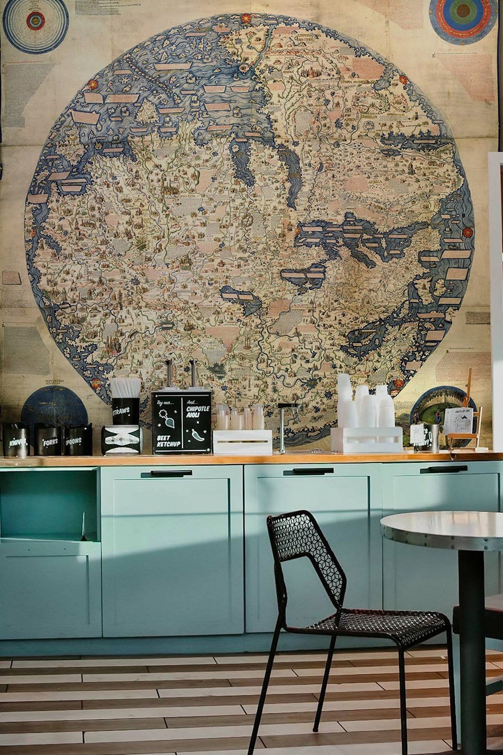 Vintage World Map Mural Wallpaper, vintage decor, mint cabinets, black chair, wooden flooring, kitchen setting.