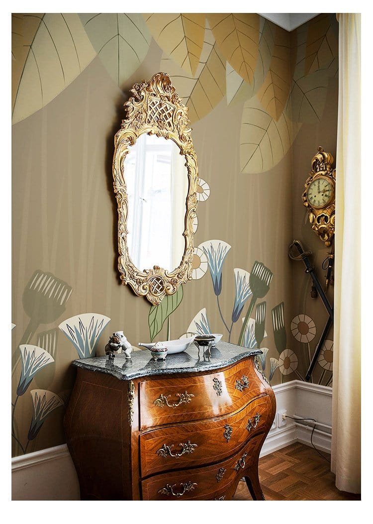 Botanical Harmony Mural Wallpaper with earthy leaves, floral patterns, ornate mirror, antique dresser in room.