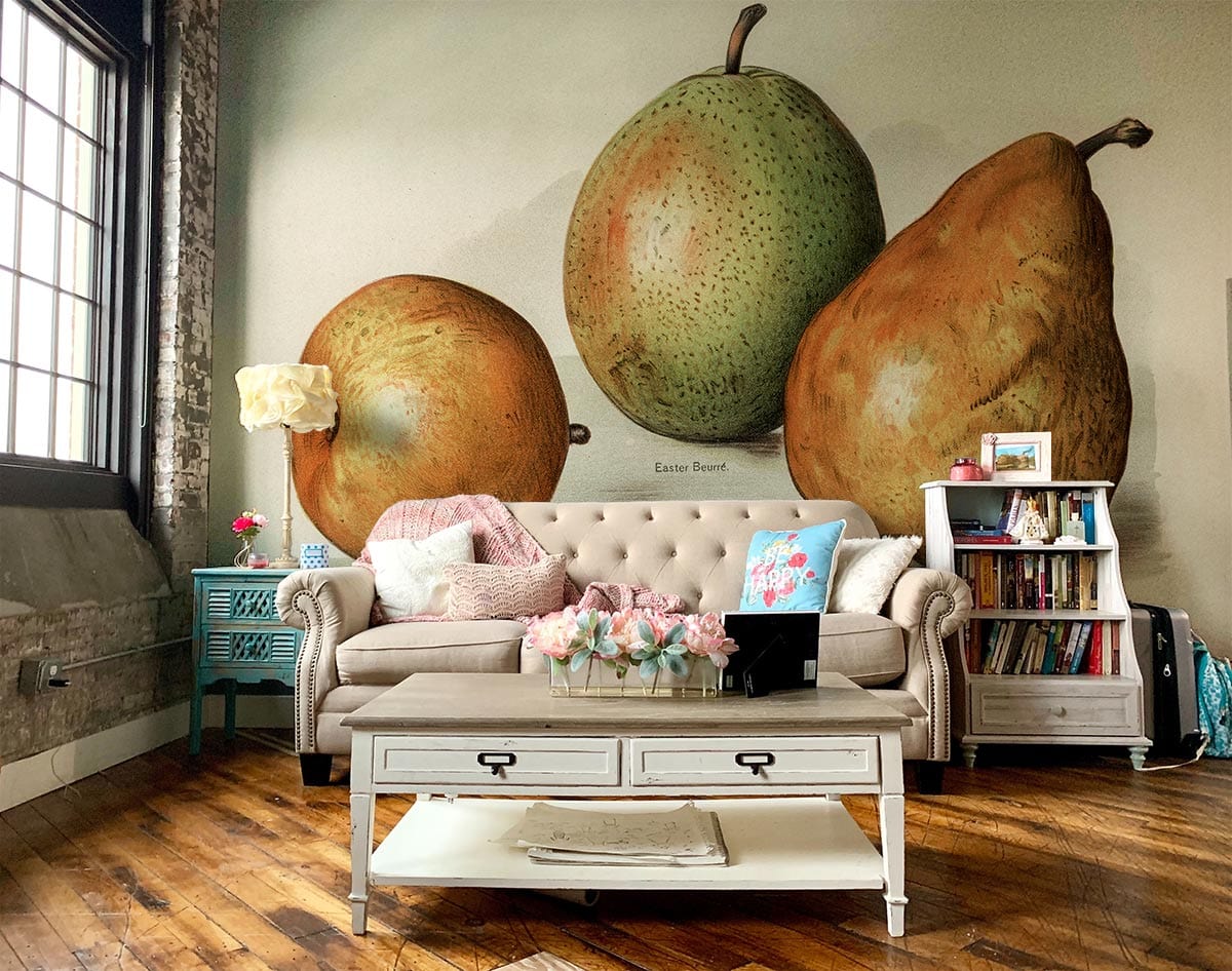 Cosy living room with Vintage Pear Botanical Print Wallpaper, tufted beige sofa, hardwood flooring.