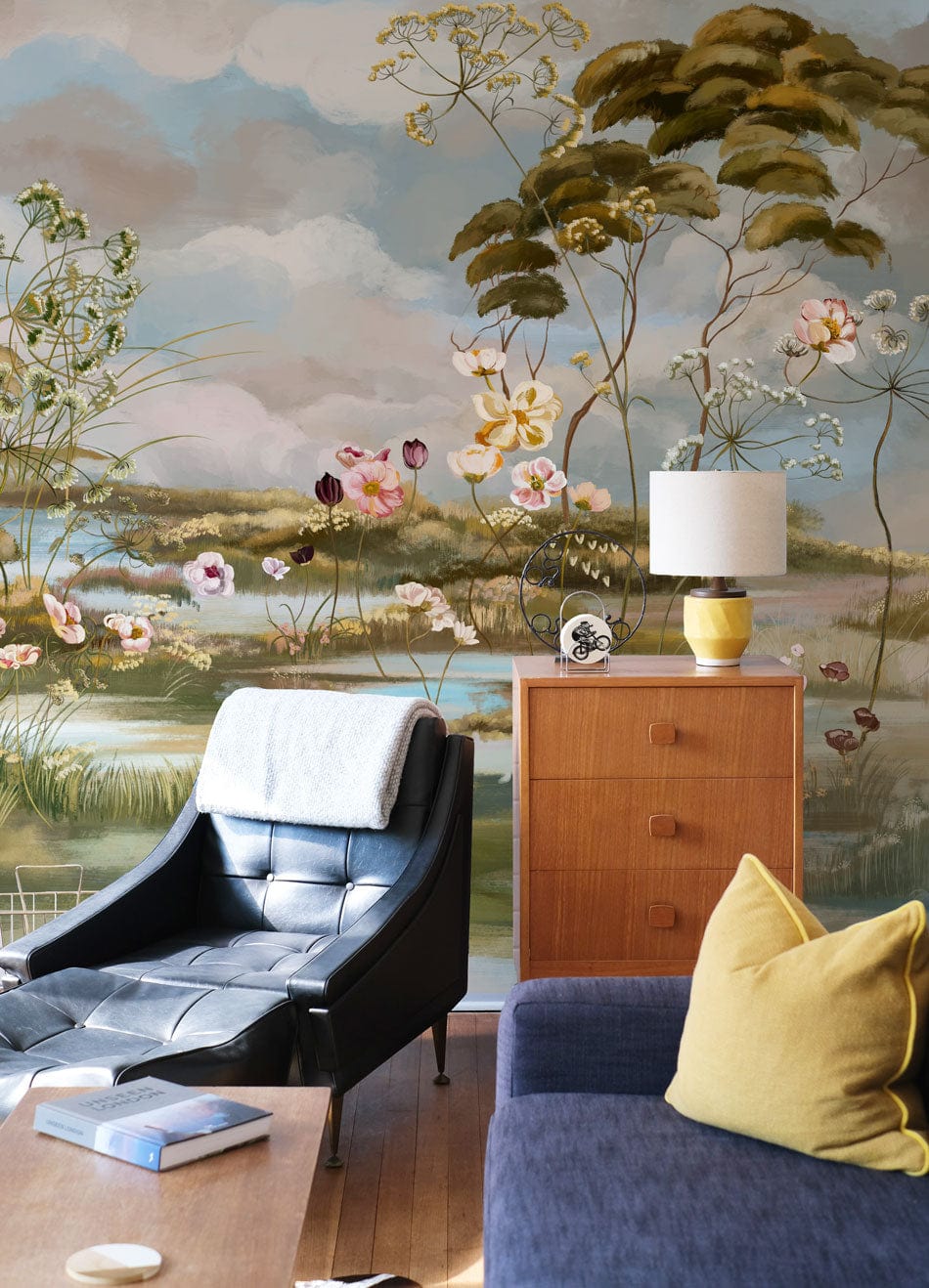 Serene Pastel Landscape Mural Wallpaper, vintage floral, black armchair, wooden flooring, cosy living room.