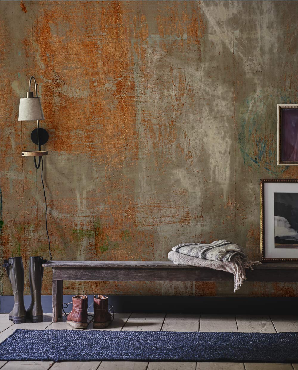 Alt text: Rustic earthy tones abstract wallpaper, industrial style, features wall lamp, bench, rug, boots.