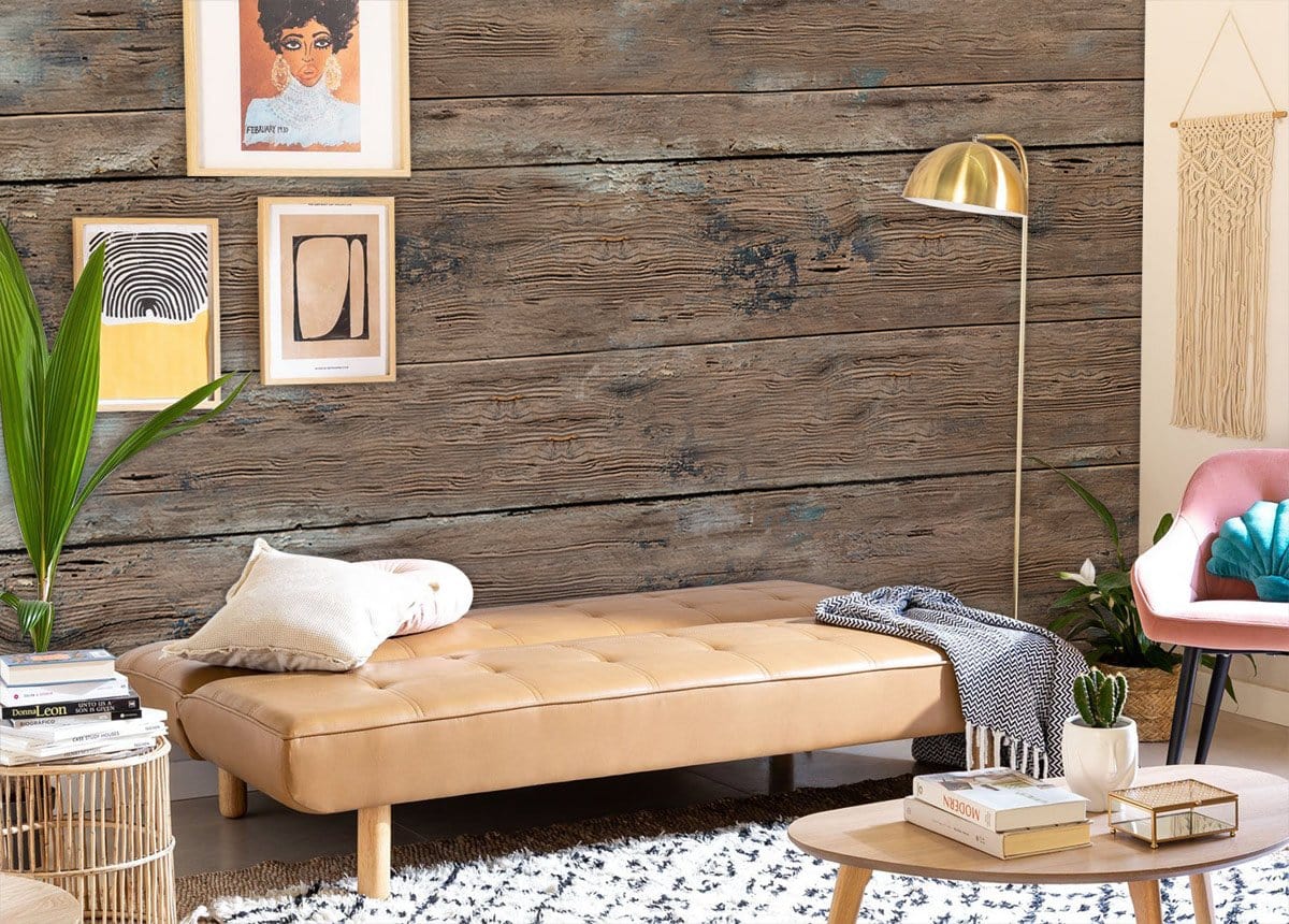 Rustic weathered wood mural wallpaper in vintage room with tan sofa, gold floor lamp, and artwork.