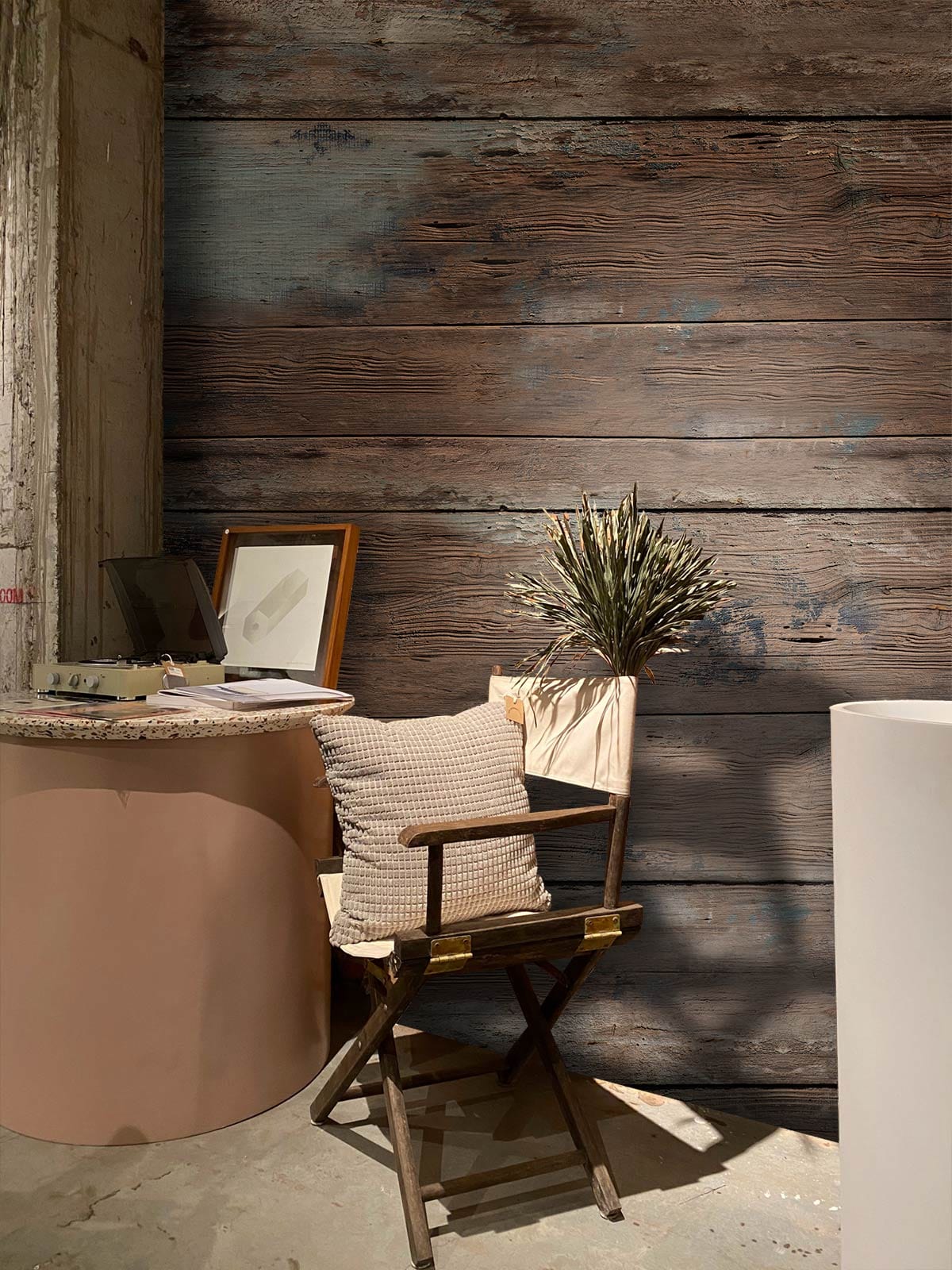 Rustic Weathered Wood Effect wallpaper with vintage chair, beige cushion, and round table in cosy room.