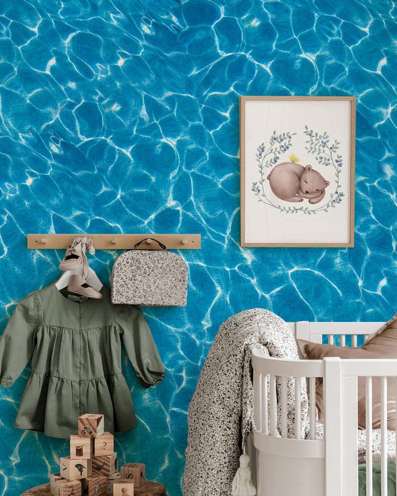 Vibrant Blue Water Ripple Wallpaper in nursery; natural wood accents, white cot, wall art decor.
