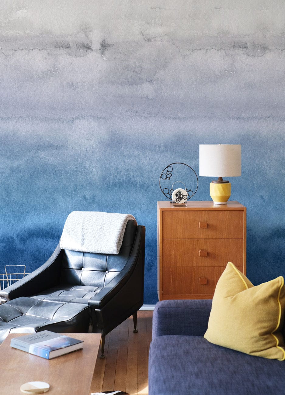 Blue Ombre Watercolour Gradient Mural Wallpaper, leather chair, mustard cushion, wooden floors, sideboard.