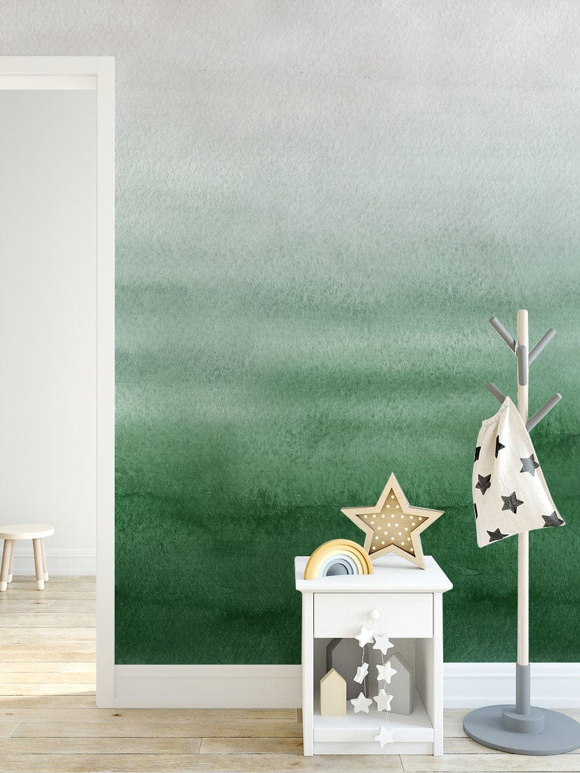 Emerald Green Watercolour Ombre Wallpaper in modern room with light wood flooring and child's furniture.