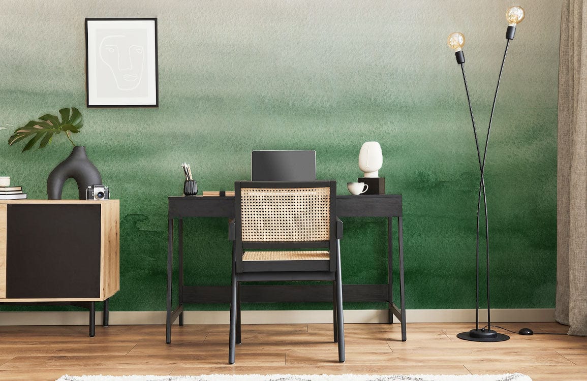 Home office with Emerald Green Watercolour Ombre Wallpaper; stylish black desk and rattan chair.