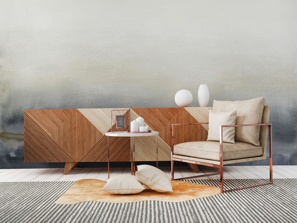 Misty Grey Ombre Watercolour Mural Wallpaper in living room with modern armchair and wooden sideboard.